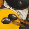 Avec les couverts à salade de la collection Souba, la lumière se glisse à table en douceur. Les manches ont été traités à chaud pour révéler un autre aspect de la corne. Et c’est ainsi que chaque couvert, pourtant composé d’une seule pièce, offre deux facettes : Le creux de la cuillère et de la fourchette, silhouettes naïves, brillent d’une satine noire. Le manche, à la teinte boisée, se veut mat et tendre au toucher. Un duo de couverts à salade bicolore, à la fois simple et moderne, d’une élégance parfaite. Des pièces réalisées à la main, dotées d’un charme au naturel déconcertant. C’est la promesse de composer une table unique, sans frontières.